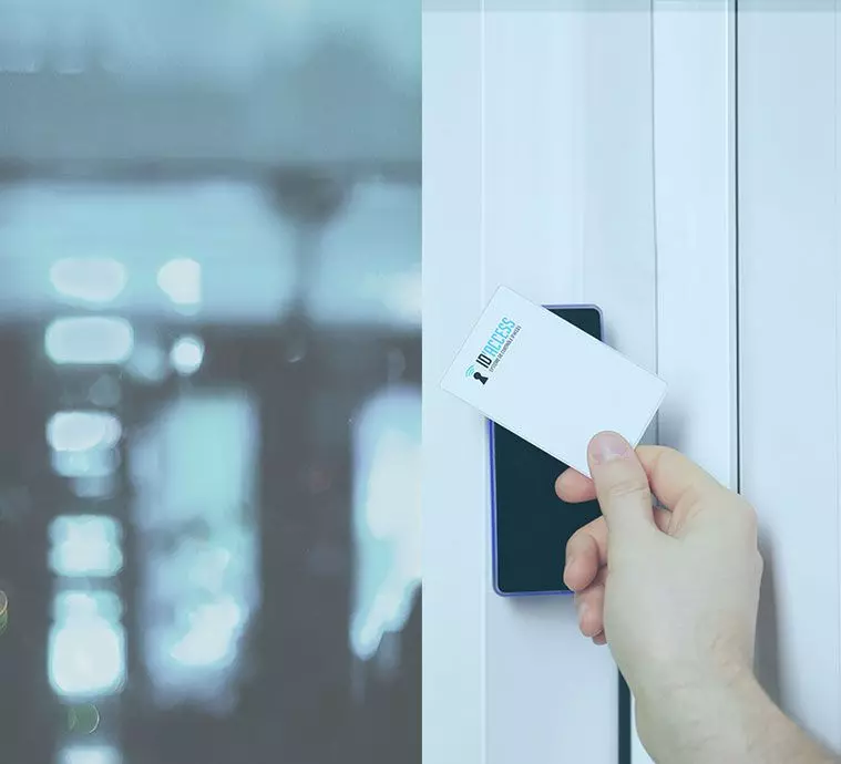 Une main tenant un téléphone avec une carte d'accès, prête à scanner un lecteur sur une porte blanche.